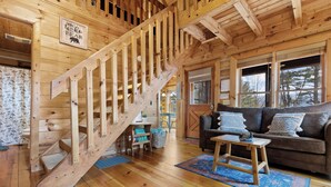A wooden interior with a staircase, a sofa, and a rug.