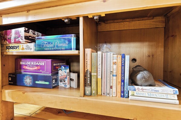 A wooden shelf with board games and books, a small figurine, and a smoke detector. - Romantic Blue Ridge Cabin, Secluded Hot Tub, King Bed, Mt. Views- Dog Friendly! (Blue Ridge)