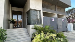 A modern building with a concrete facade, large windows, and a staircase leading to the entrance. - Waypoint Suites (Dakar)