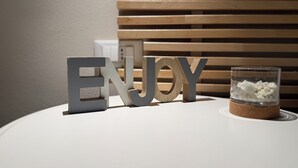Pöydällä on puisia kirjaimia, joista on muodostettu sana ”ENJOY”, sekä lasipurkki, jossa on valkoisia esineitä.