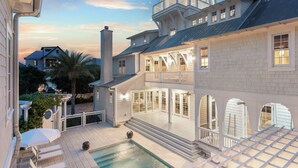 A large, multi-story house with a pool, outdoor seating, and a balcony.