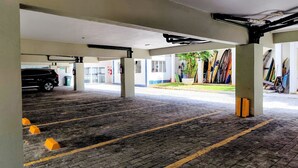 Un'area di parcheggio interna con un'auto nera parcheggiata, pilastri in cemento e pavimento piastrellato.