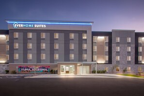 Un moderno edificio de hotel con el letrero "Everhome Suites" y un mural del paisaje de Yuma, Arizona.