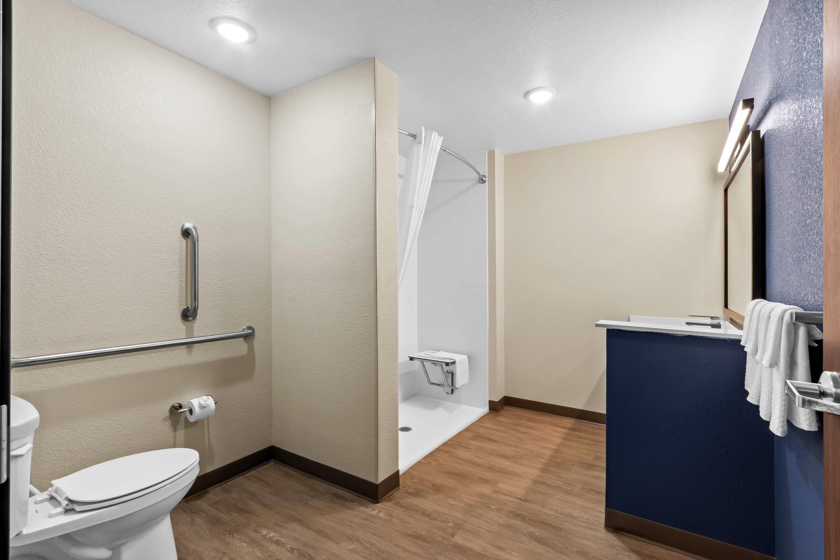A bathroom with a toilet, a shower with a glass door, a sink with a mirror, and a towel rack.