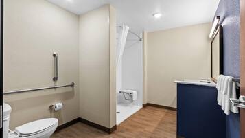 A bathroom with a toilet, a shower with a glass door, a sink with a mirror, and a towel rack.