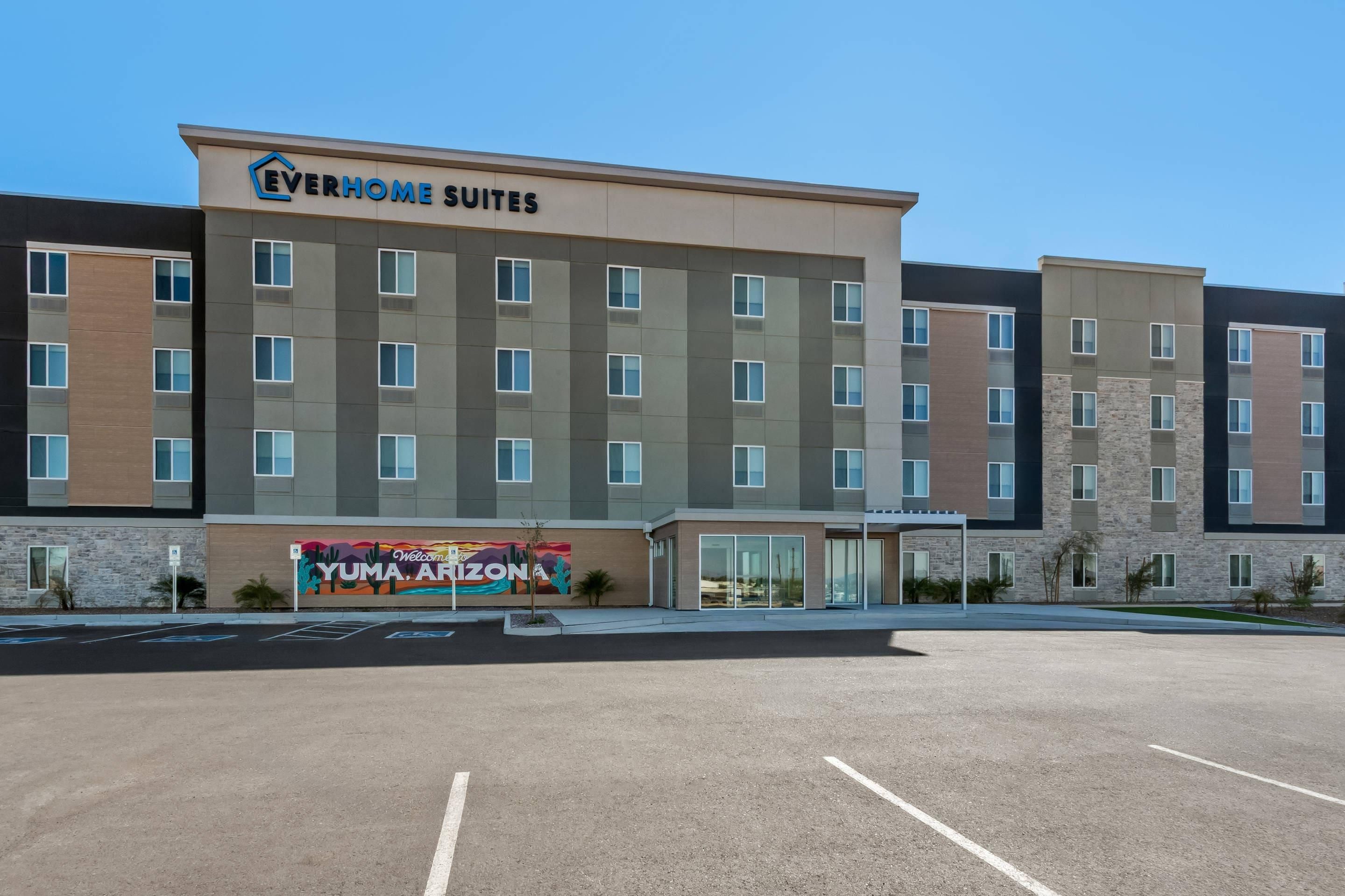 A modern hotel with multiple floors, a welcoming mural, and a clear parking area.