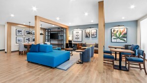 Een moderne woonkamer met een blauwe bank, houten vloeren en ingelijste foto’s aan de muren.