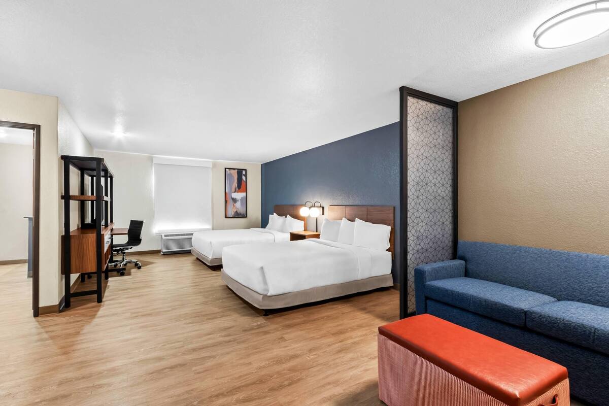 Een hotelkamer met twee bedden, een bureau, een stoel, een bank en een kleine tafel.