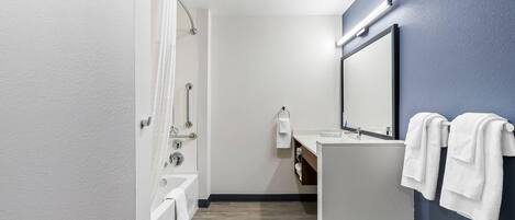 A modern bathroom with a bathtub, a sink, and a mirror.