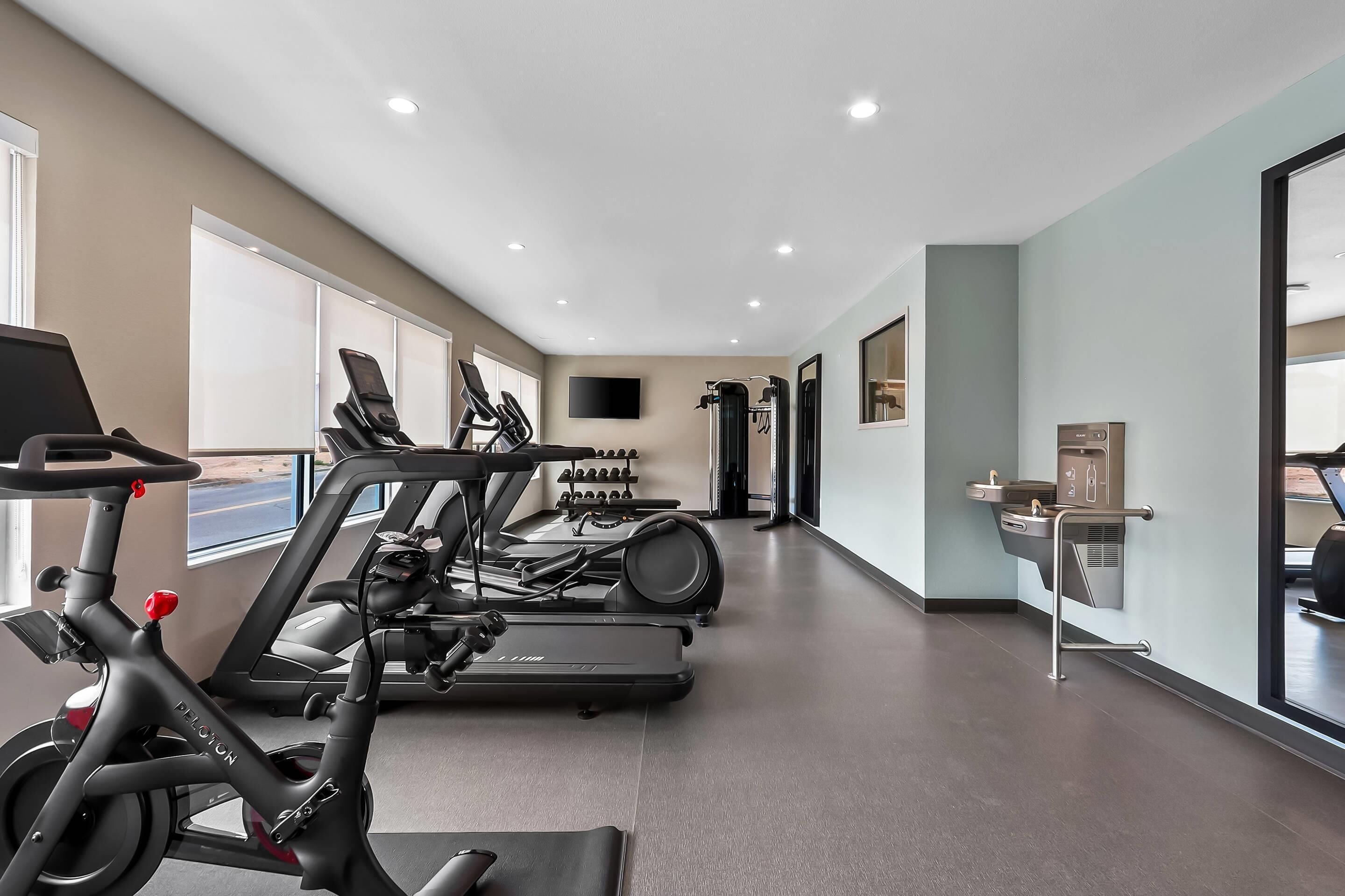 A gym with exercise equipment, including treadmills and stationary bikes, and a wall-mounted television.
