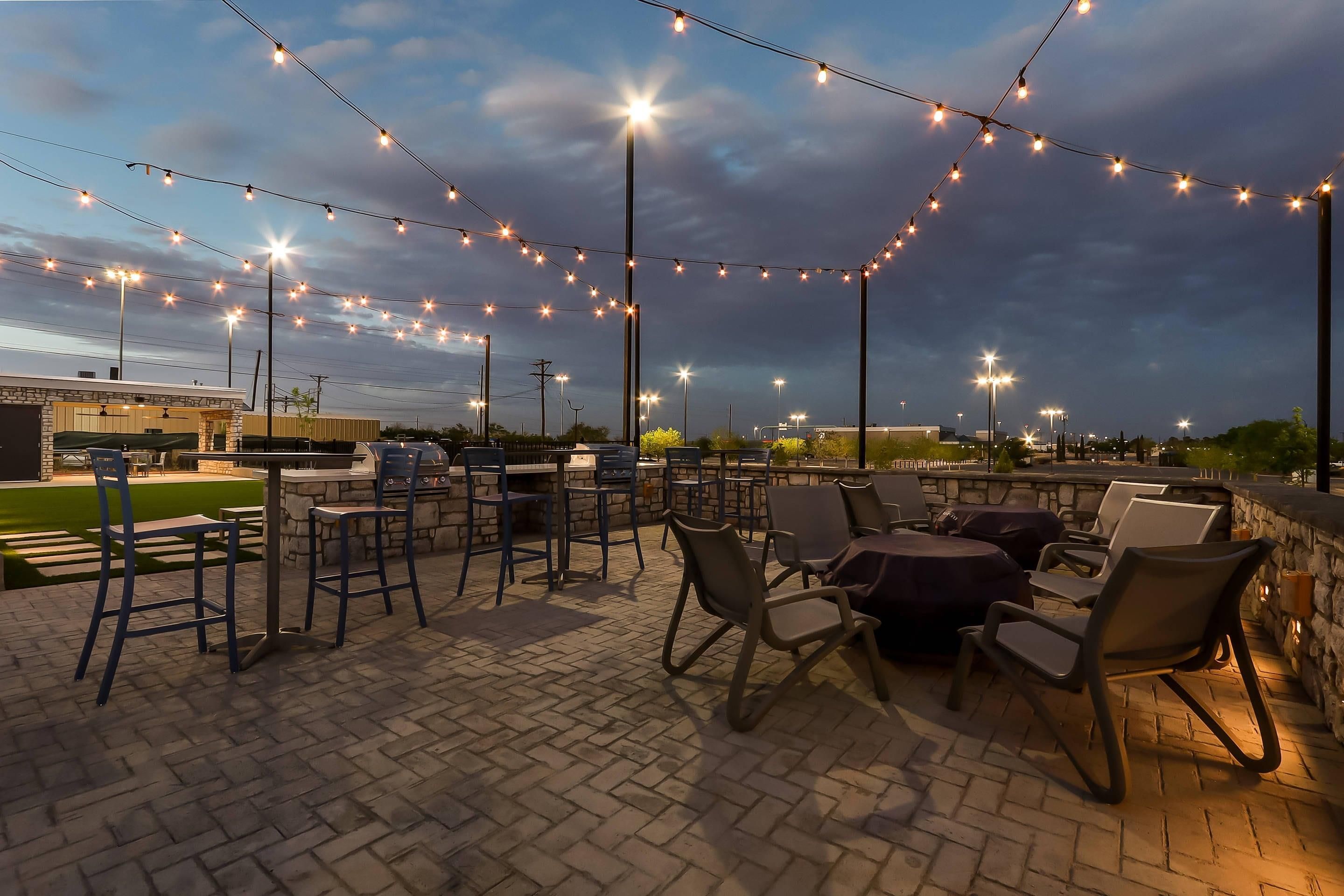 An outdoor patio with string lights, outdoor seating, and a brick floor.
