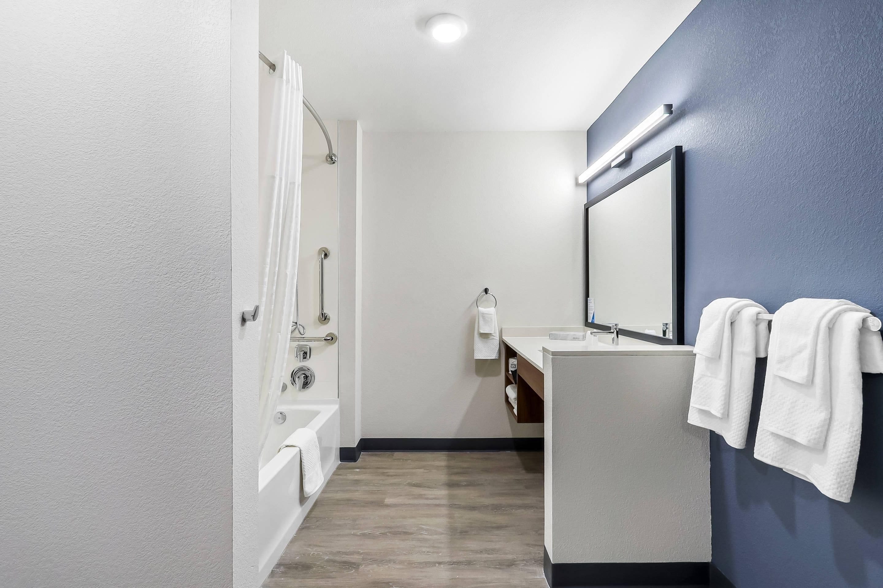 Een moderne badkamer met een bad, een wastafel en een spiegel.