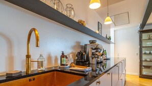A modern kitchen with a black countertop, gold faucet, and stainless steel appliances. - Heart of the city Penthouse with rooftop terrace (København)