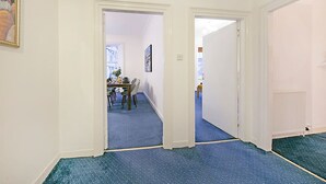 A hallway with a dining area, a painting on the wall, and a radiator. - Castle Street Apartments | Grampian Lettings Ltd (Aberdeen)
