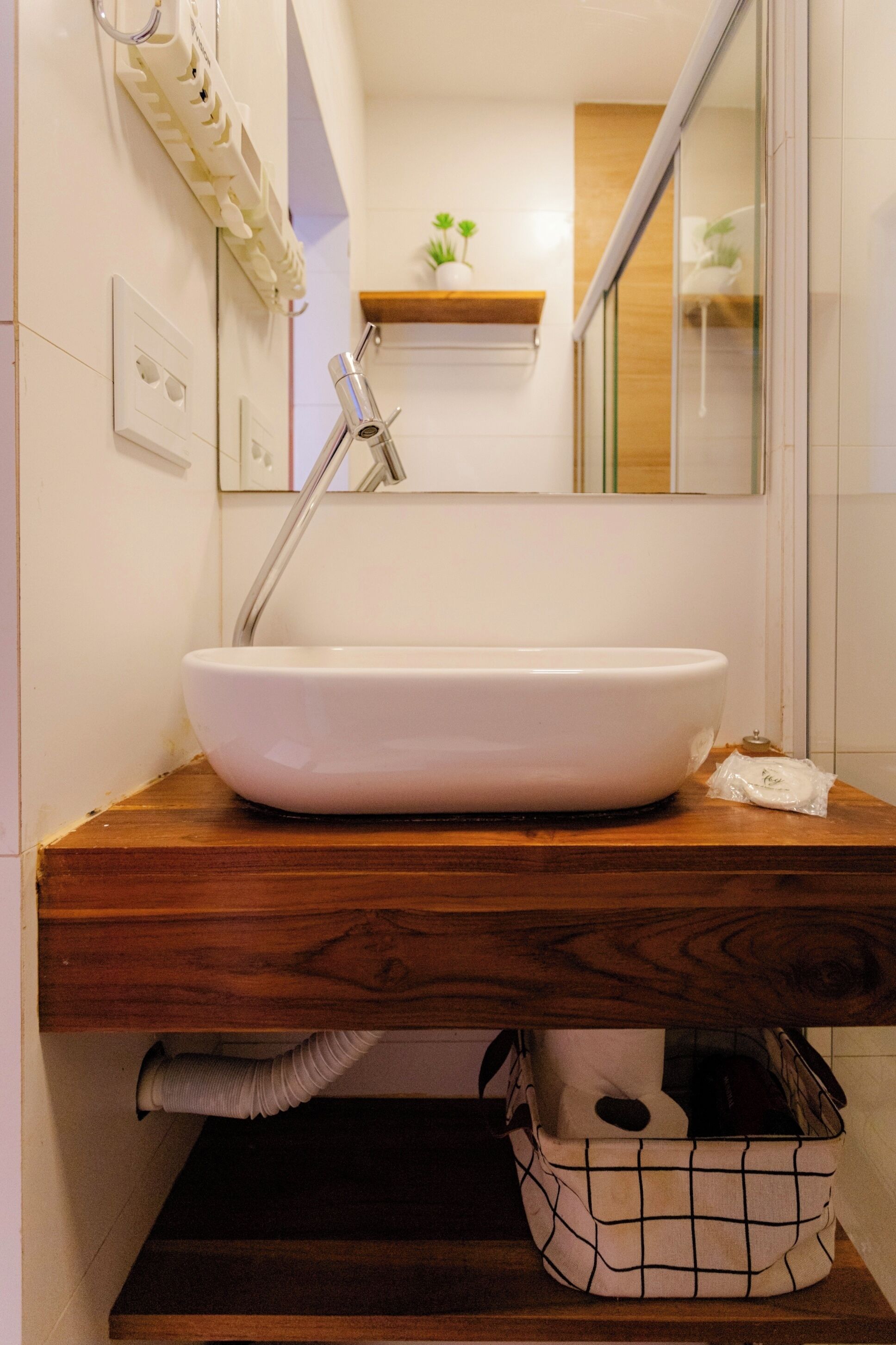 A bathroom with a white sink, wooden countertop, and a mirror above it.