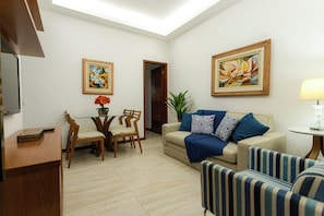 A living room with a sofa, striped armchairs, a coffee table, a dining table with chairs, and two paintings on the walls. - Ladeira dos Tabajaras 140 (Rio de Janeiro)