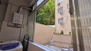 Une petite salle de bain avec une fenêtre, une baignoire et une vue dégagée sur l’extérieur, avec un bâtiment et de la verdure.