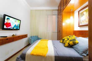 A hotel room with a bed, a television, a wooden headboard, a window with curtains, and a wall-mounted shelf. - Ladeira dos Tabajaras 140 (Rio de Janeiro)