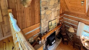 Ein Blockhaus-Interieur mit Kamin aus Stein, Holzwänden und einem aufgehängten Hirschkopf.