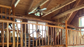 Ein rustikales Ferienhaus im Inneren mit Holzbalkon, Essbereich und Küche.