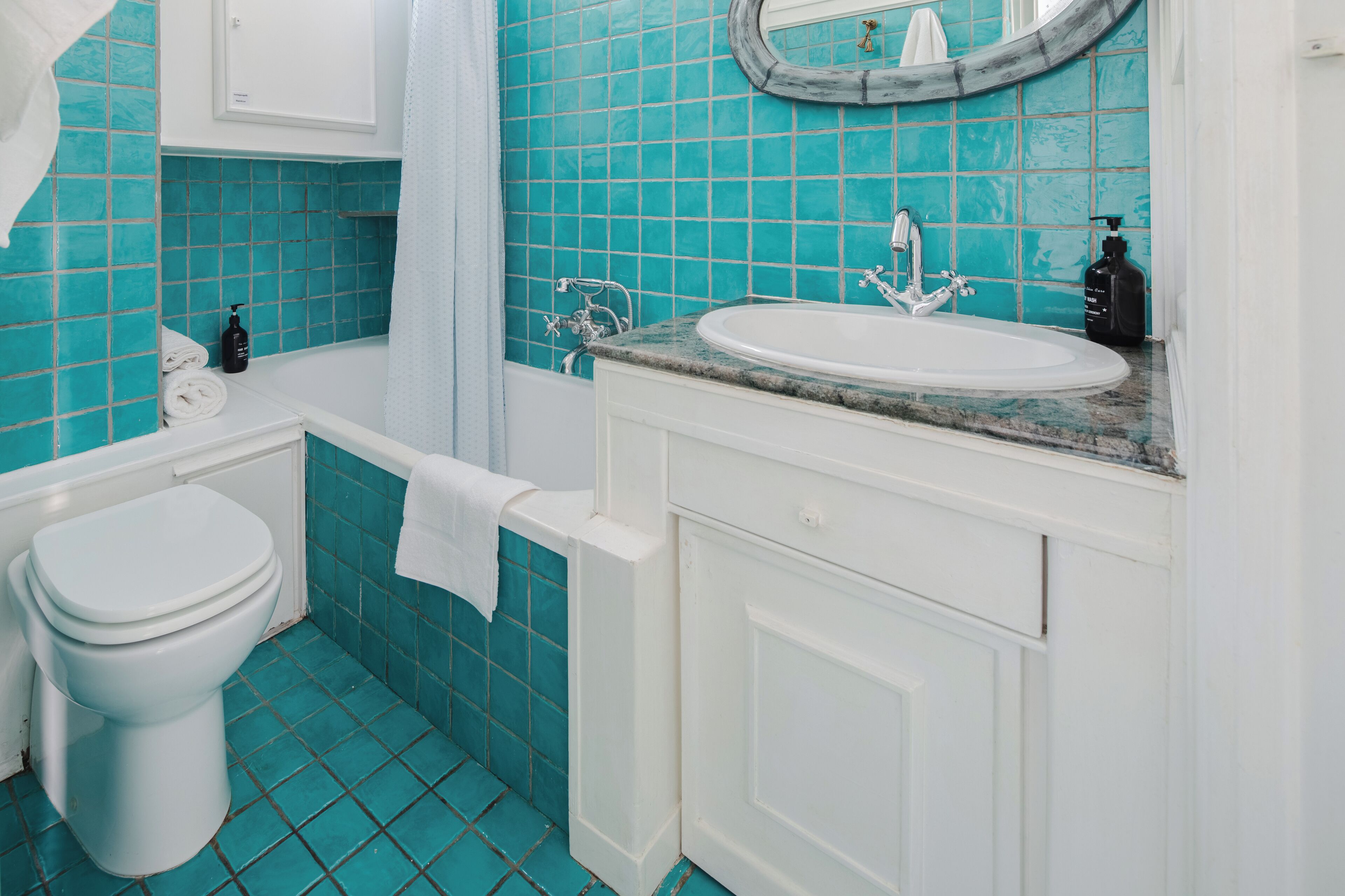 A bathroom with a white toilet, a bathtub, a sink with a marble countertop, and a mirror above the sink.