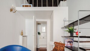 A modern interior with a blue chair, a white bench, and a metal shelf with decorative items. - DADI INN MONTI (Rome)