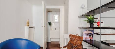 A modern interior with a blue chair, a white bench, and a metal shelf with decorative items.