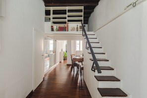 Un escalier menant à une mezzanine dotée d’un plancher en bois et de murs blancs.