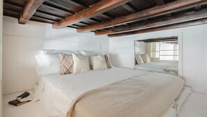 A bedroom with a large bed, wooden beams on the ceiling, a mirror, and a window. - DADI INN MONTI (Rome)