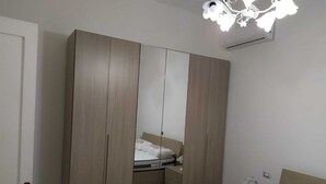 Een slaapkamer met een grote garderobe, een bed en een plafondlamp.