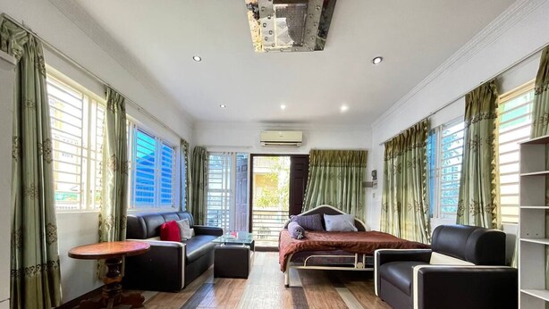 A spacious room with a bed, two sofas, a small table, and a bookshelf. - Cassiarata (Phnom Penh)