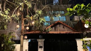 A gated entrance with a tiled roof, a black gate, and a motorcycle parked in front. - Cassiarata (Phnom Penh)