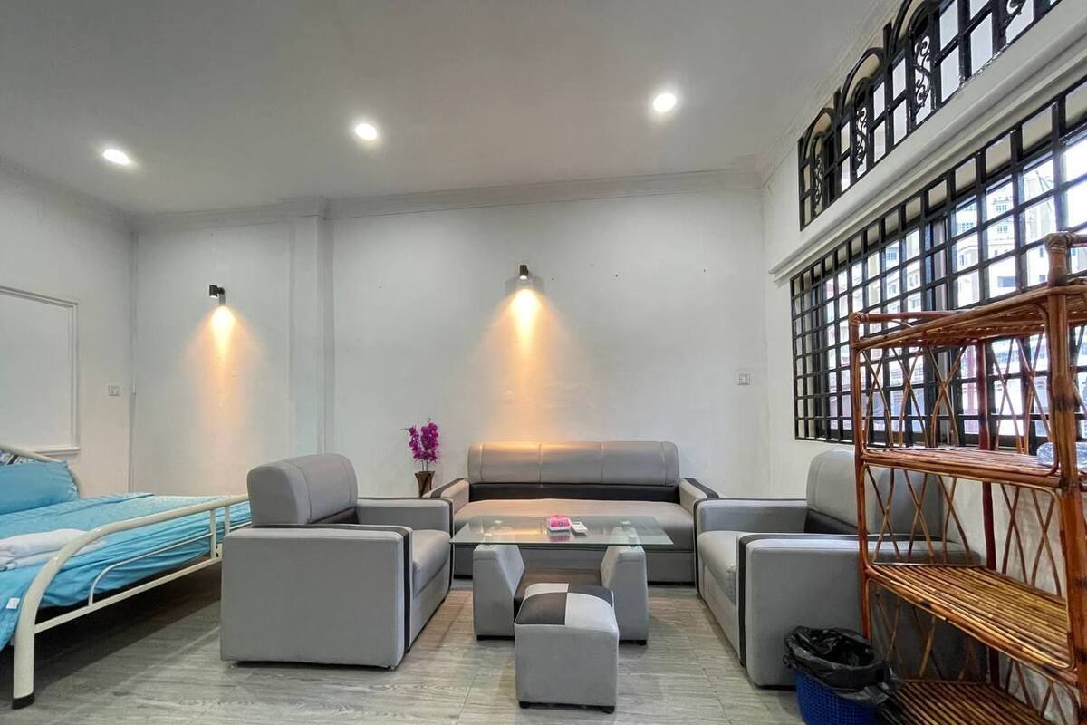 A modern living room with a sofa set, a coffee table, and a bed with a blue headboard.