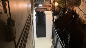 A narrow stairway with a metal railing, a wall-mounted radiator, and a door at the end. - Cassiarata (Phnom Penh)
