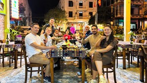 A group of people dining at an outdoor restaurant with tiled flooring and patterned tablecloths. - The Palm Lodge (Phong Nha)