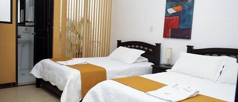 Habitación de hotel con dos camas, un baño y un cuadro en la pared.
