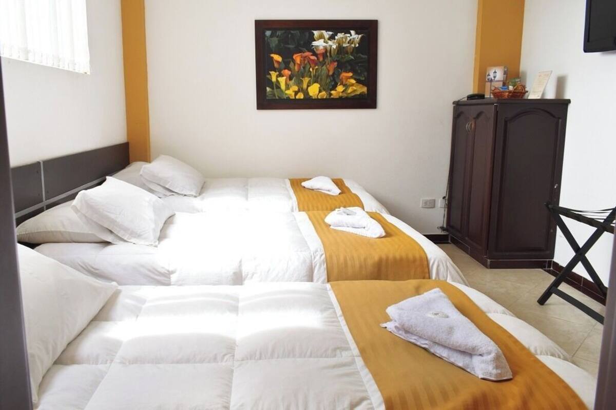 A hotel room with two beds, a wooden cabinet, and a framed picture on the wall.