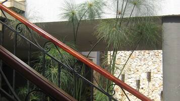 Stairs lead to an upper level, surrounded by lush greenery and a stone wall.