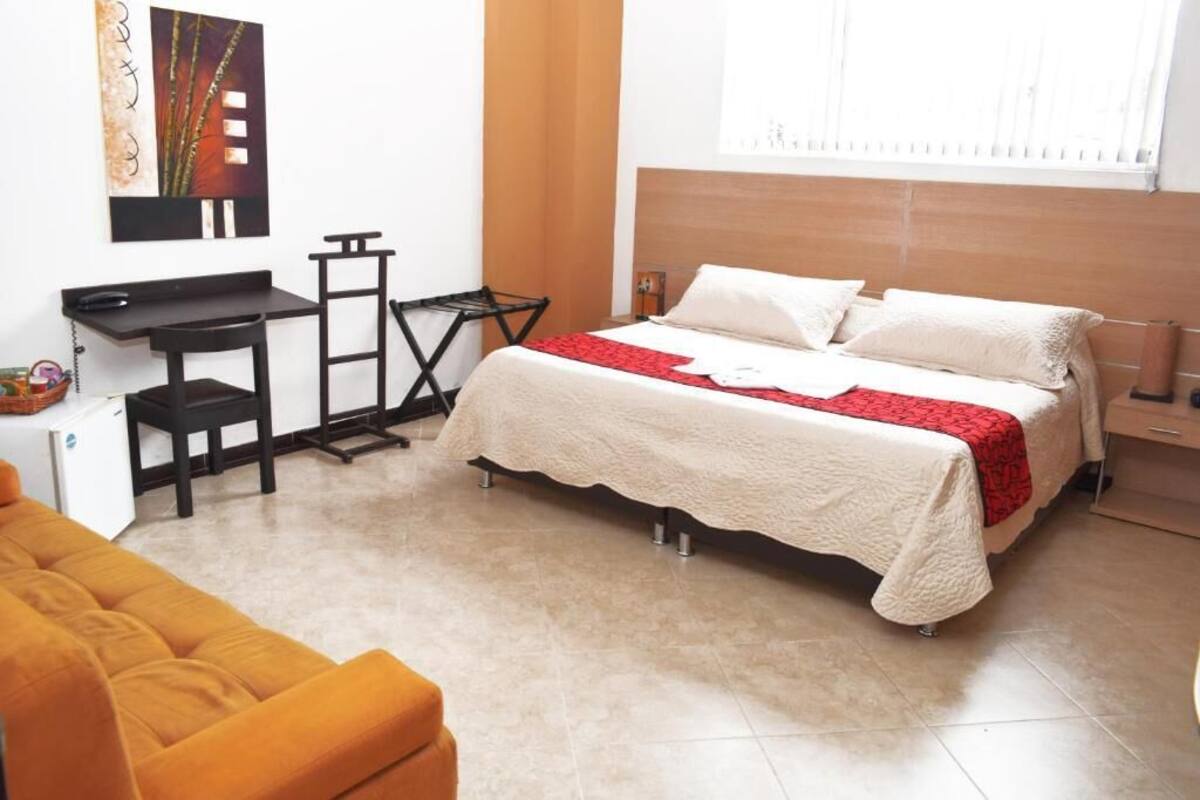 A bedroom with a bed, a desk, and a chair.