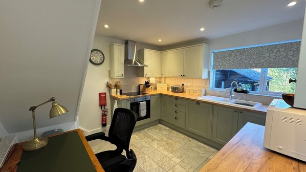 A compact kitchen with a built-in oven, a sink, and a window with a view of the outdoors. - Luxury Country Cottage Retreat – Perfect for Romantic Getaways & Family Holidays, with Easy Access to Scenic Walks, Horsham’s Attractions, and Sussex’s Best Markets & Dining Experiences. (Horsham)