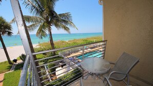 A balcony with a pool, chairs, and a view of the beach and ocean. - 3-bedroom, 3 bath condo in beautiful Longboat Key. Beachfront views w/ pool. (Longboat Key)