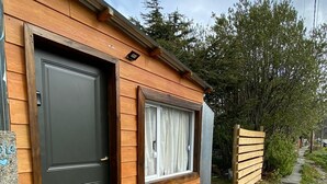 A wooden cabin with a dark door and a window with curtains.