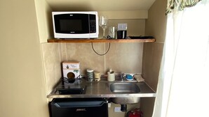 A compact kitchenette with a microwave, coffee maker, and small sink.