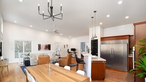 Una cocina moderna con refrigerador de acero inoxidable, mesa de comedor de madera y una araña.