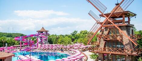 A resort with a large pool, windmill, and water slide.