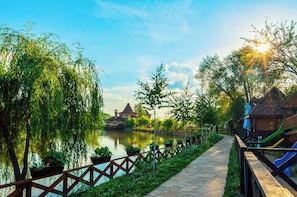 A riverside walkway with a wooden fence, a small building, and a playground with slides. - Windmills Resort (Gorna Malina)