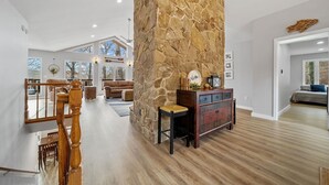 Un vaste espace de vie agrémenté d’un mur en pierre, d’un escalier en bois et d’un coin salon confortable.