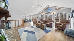 Un salon spacieux avec un plafond haut, une grande fenêtre et une vue sur l’extérieur.