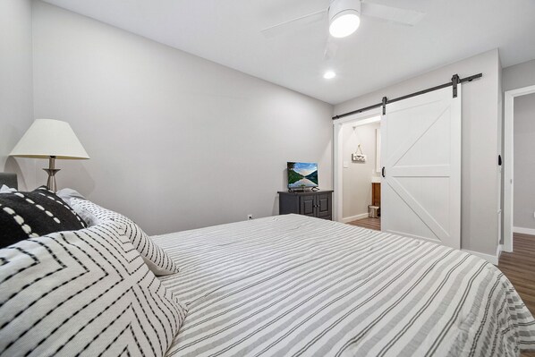 A bedroom with a bed, a lamp, a TV, and a sliding door. - Suits Us Too with its easy access to private dock on Norris Lake Big Creek (LaFollette)