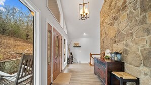 Une terrasse en bois avec un banc, un mur en pierre et un autre banc en bois agrémenté d’un coussin.